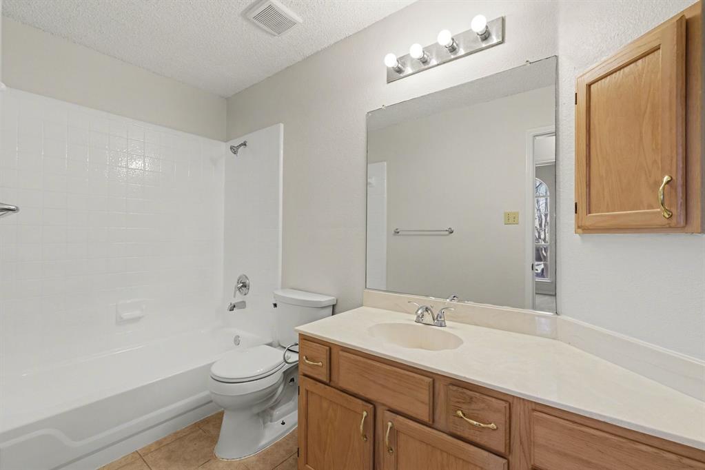 6921 Hominy Ridge Rowlett, TX 75089 - Photo 23 of 27 a bathroom with a granite countertop sink a toilet and a mirror