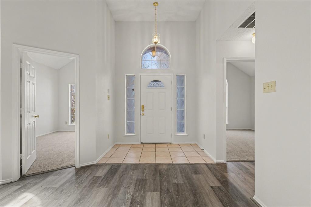 6921 Hominy Ridge Rowlett, TX 75089 - Photo 3 of 27 a view of a hallway with wooden floor and a chandelier