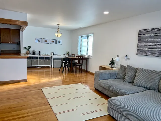 a living room with furniture and a dining table with wooden floor