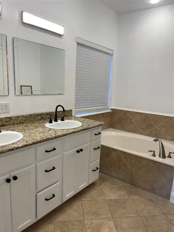 a bathroom with a granite countertop sink and a bathtub