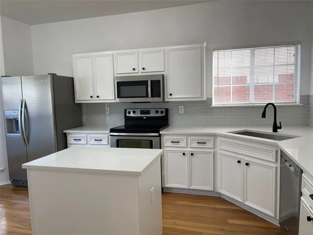 a kitchen with stainless steel appliances a stove a sink a microwave and cabinets