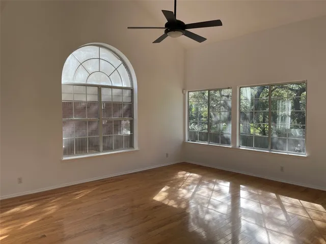 an empty room with wooden floor exposed radiator and windows