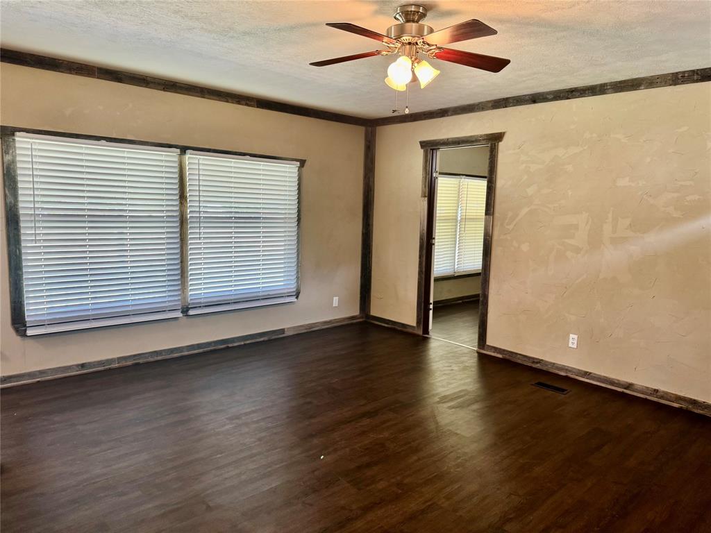 934 Tiffany Street Azle, TX 76020 - Photo 7 of 25 an empty room with wooden floor chandelier fan and windows