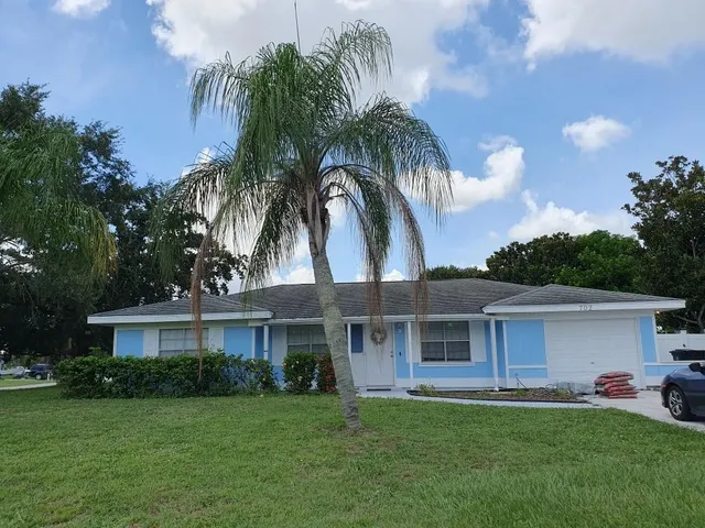 a front view of a house with a garden and trees