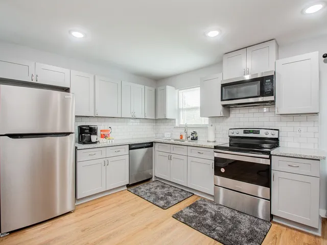 a kitchen with granite countertop white cabinets and stainless steel appliances