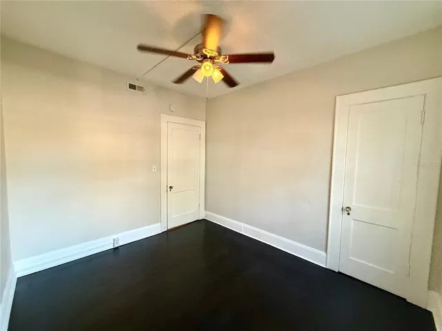 a view of a small space with wooden floor and a ceiling fan