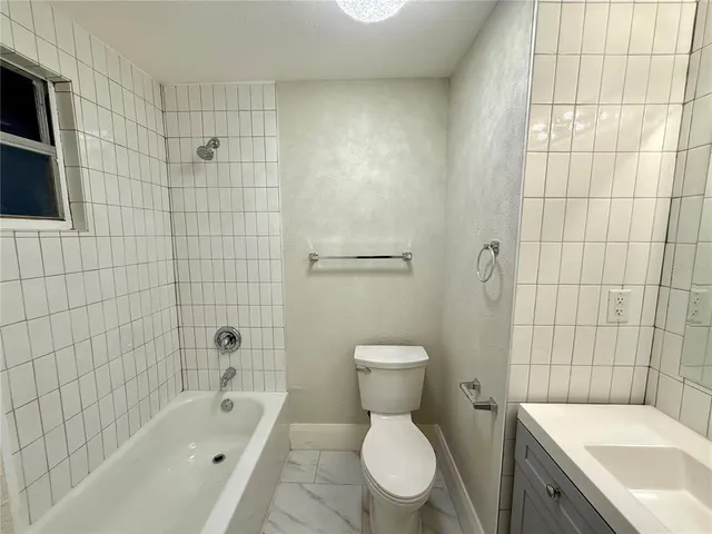 a white toilet sitting next to a bath tub and shower