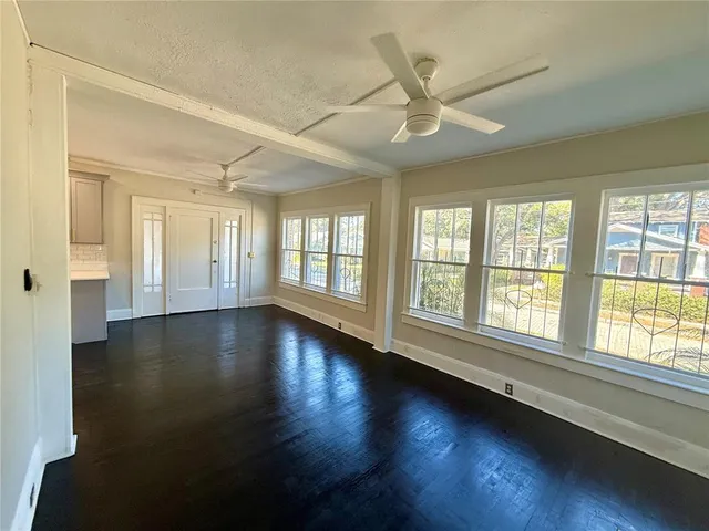 a view of an empty room with wooden floor and a window