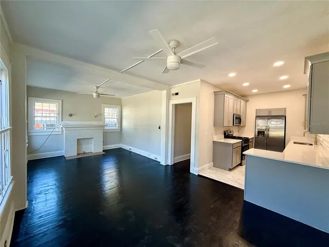 a view of a big room with wooden floor and a kitchen