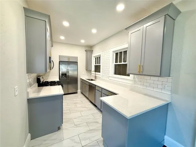 a large white kitchen with a large counter top appliances and cabinets