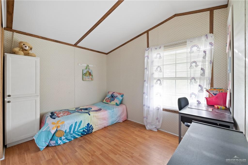 27516 Glenview Road Rio Hondo, TX 78583 - Photo 13 of 26 Bedroom featuring vaulted ceiling, light wood finished floors, wallpapered walls, and ornamental molding