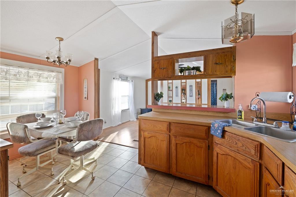 27516 Glenview Road Rio Hondo, TX 78583 - Photo 7 of 26 Kitchen featuring a chandelier, light countertops, hanging light fixtures, brown cabinetry, and light tile patterned flooring