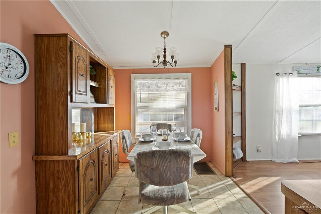 27516 Glenview Road Rio Hondo, TX 78583 - Photo 9 of 26 Dining room with a chandelier, healthy amount of natural light, light tile patterned floors, and crown molding