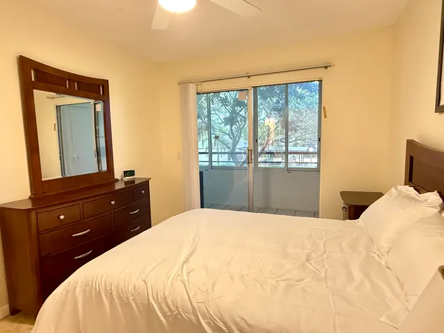 a bedroom with a bed and a large mirror next to a window