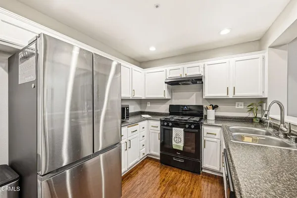 a kitchen with stainless steel appliances granite countertop a hardwood floor sink stove and refrigerator