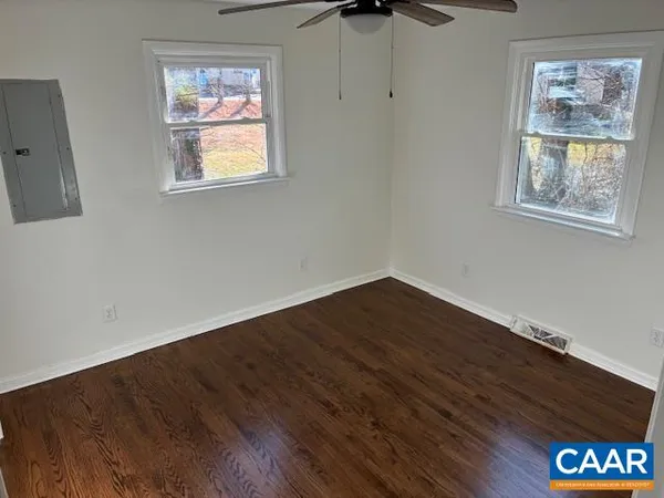 a view of an empty room with wooden floor and a window