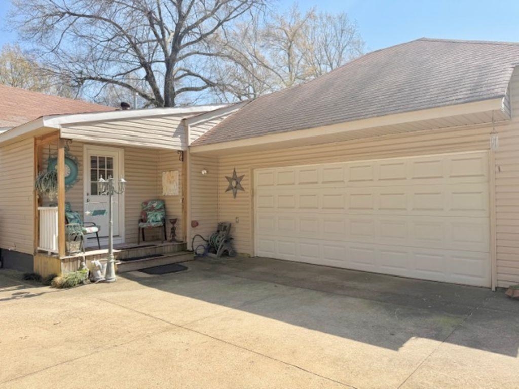 829 North Perkins Road Memphis, TN 38122 - Photo 30 of 36 View of side of property featuring concrete driveway, a shingled roof, an attached garage, and covered porch
