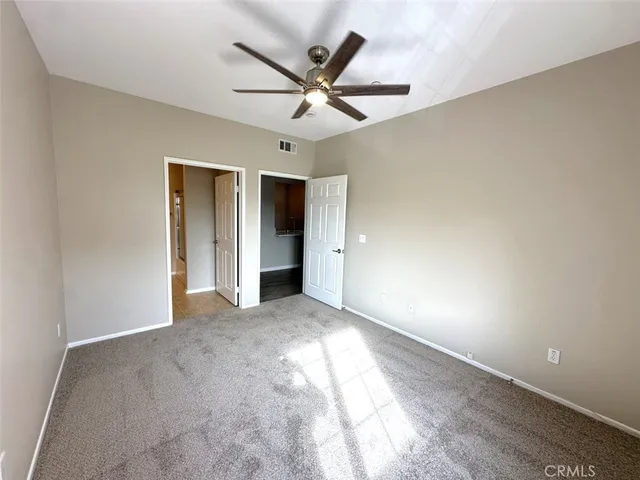 an empty room with closet and ceiling fan