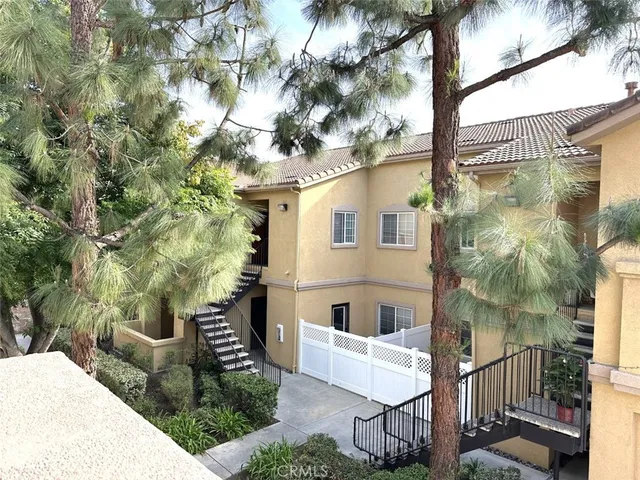 a view of a white house with a tree and wooden fence