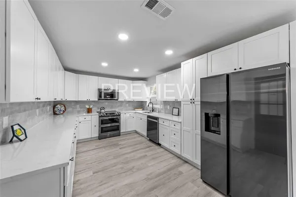 a kitchen with stainless steel appliances a refrigerator sink and white cabinets