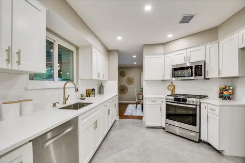a kitchen with white cabinets and stainless steel appliances