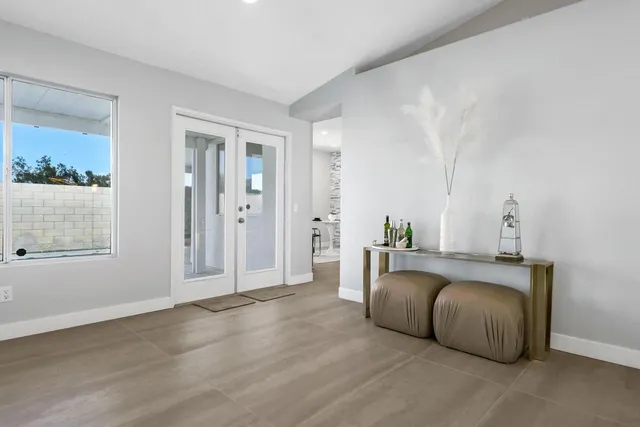 a kitchen with granite countertop lots of white cabinets a sink dishwasher a dining table and chairs with wooden floor