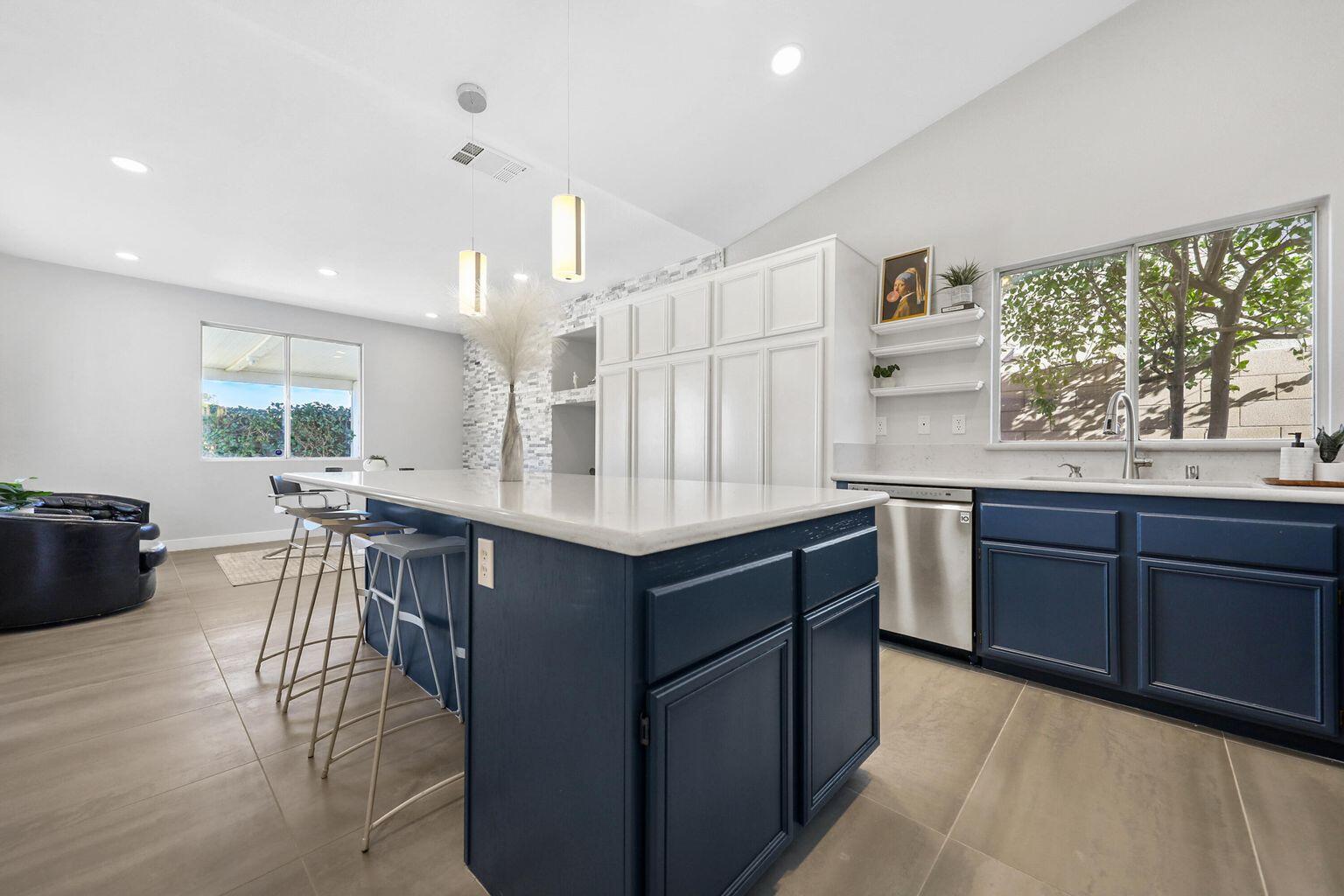 Undisclosed Address Palm Desert, CA 92211 - Photo 10 of 31 a kitchen with granite countertop lots of white cabinets a sink dishwasher a dining table and chairs with wooden floor
