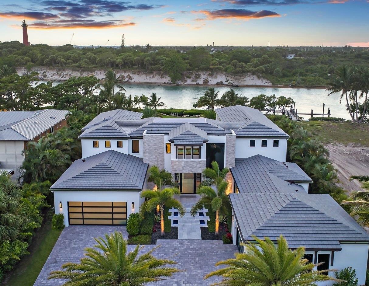 102 Lighthouse Drive Jupiter Inlet Colony, FL 33469 - Photo 1 of 18 a front view of a house with a garden and plants