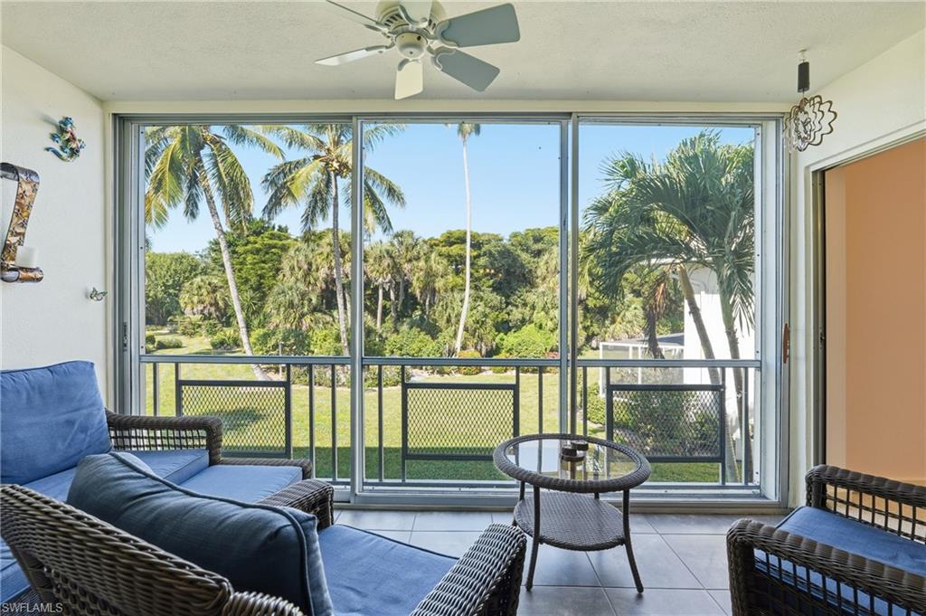 215 Cypress Way East, Unit D8 Naples, FL 34110 - Photo 5 of 20 Sunroom featuring tile patterned flooring, view of scattered trees, and a textured ceiling