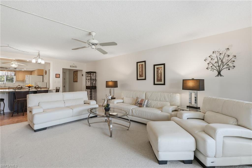 215 Cypress Way East, Unit D8 Naples, FL 34110 - Photo 6 of 20 Living area with ceiling fan, a chandelier, and a textured ceiling