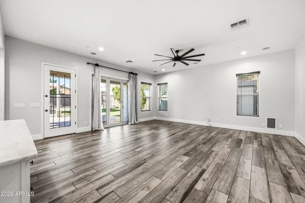 a kitchen with stainless steel appliances granite countertop a refrigerator a stove a sink and white cabinets with wooden floor