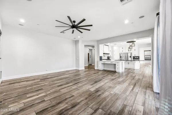 a large kitchen with stainless steel appliances kitchen island granite countertop a stove a sink a refrigerator and white cabinets with wooden floor