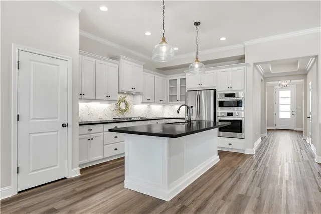 a kitchen with stainless steel appliances kitchen island granite countertop a lot of counter space and wooden floors