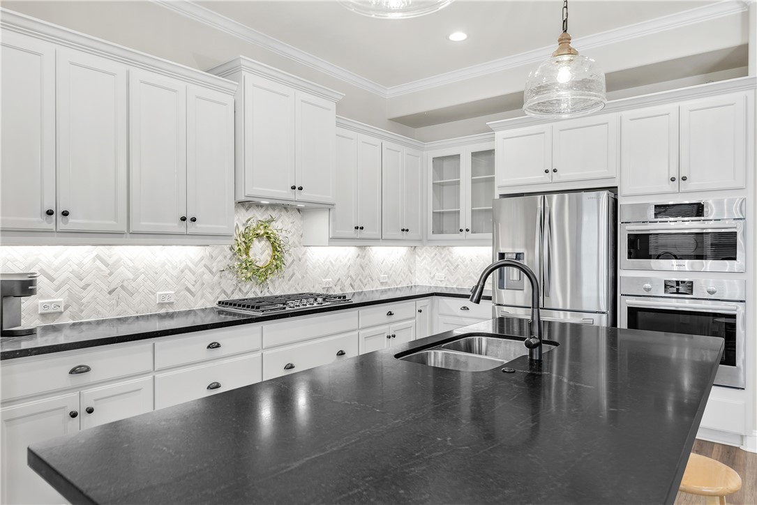 4355 Fox River Lane Bryan, TX 77802 - Photo 5 of 36 a kitchen with granite countertop a refrigerator a stove a sink and white cabinets with wooden floor