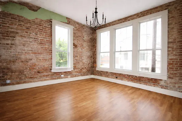 a view of an empty room with a window and wooden floor