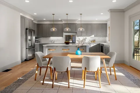a dining room with stainless steel appliances kitchen island granite countertop a dining table chairs and a refrigerator