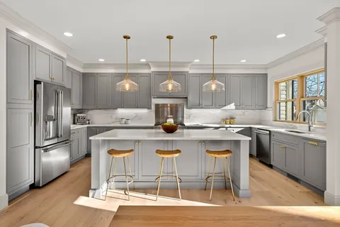 a kitchen with stainless steel appliances kitchen island granite countertop a dining table chairs and wooden floor