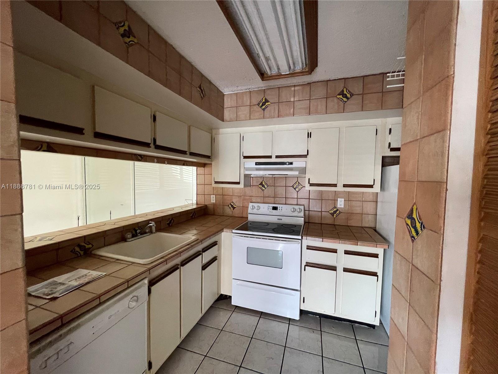 18216 Mediterranean Boulevard, Unit 119 Hialeah, FL 33015 - Photo 35 of 42 a kitchen with white cabinets and appliances