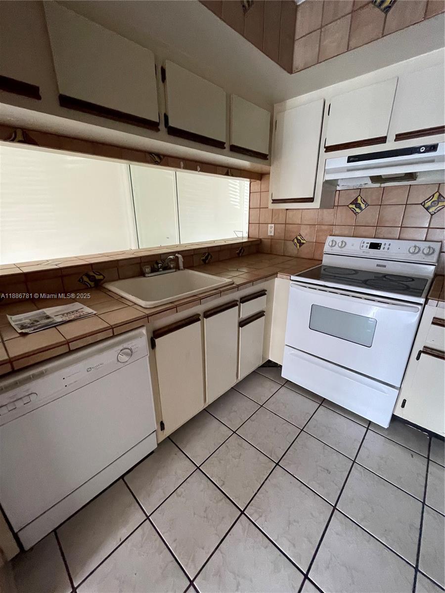 18216 Mediterranean Boulevard, Unit 119 Hialeah, FL 33015 - Photo 36 of 42 a kitchen with granite countertop a sink and white cabinets