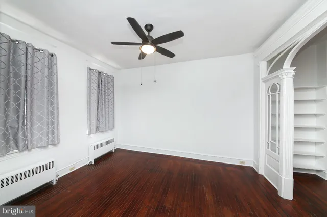a view of a livingroom with wooden floor a ceiling fan and windows