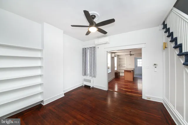a view of empty room with wooden floor and ceiling fan