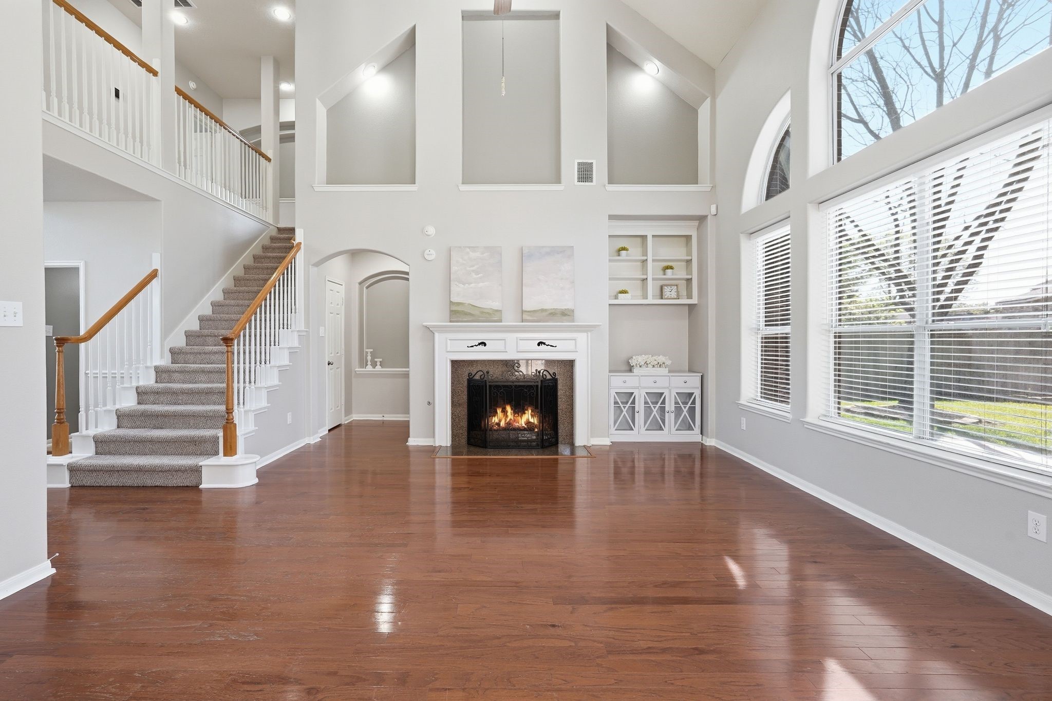 24931 Corbin Gate Drive Spring, TX 77389 - Photo 15 of 50 This spacious living room features high ceilings, a cozy fireplace, and expansive windows that provide abundant natural light. The open staircase and elegant hardwood floors add to its charm, creating a welcoming and airy atmosphere.