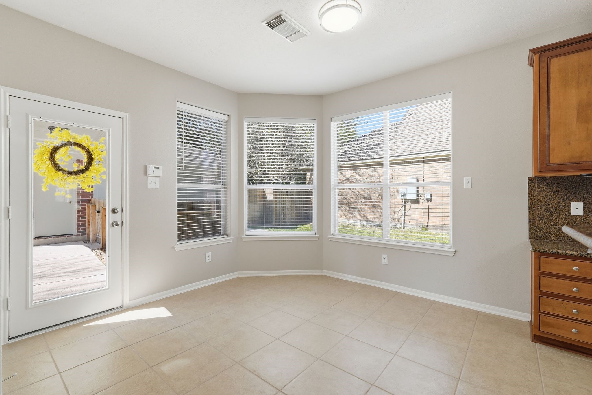 24931 Corbin Gate Drive Spring, TX 77389 - Photo 17 of 50 Bright and airy breakfast nook with large windows, tile flooring, and a door leading to your private backyard oasis. The area is adjacent to a kitchen with wooden cabinets and granite countertops. Perfect spot for morning coffee.