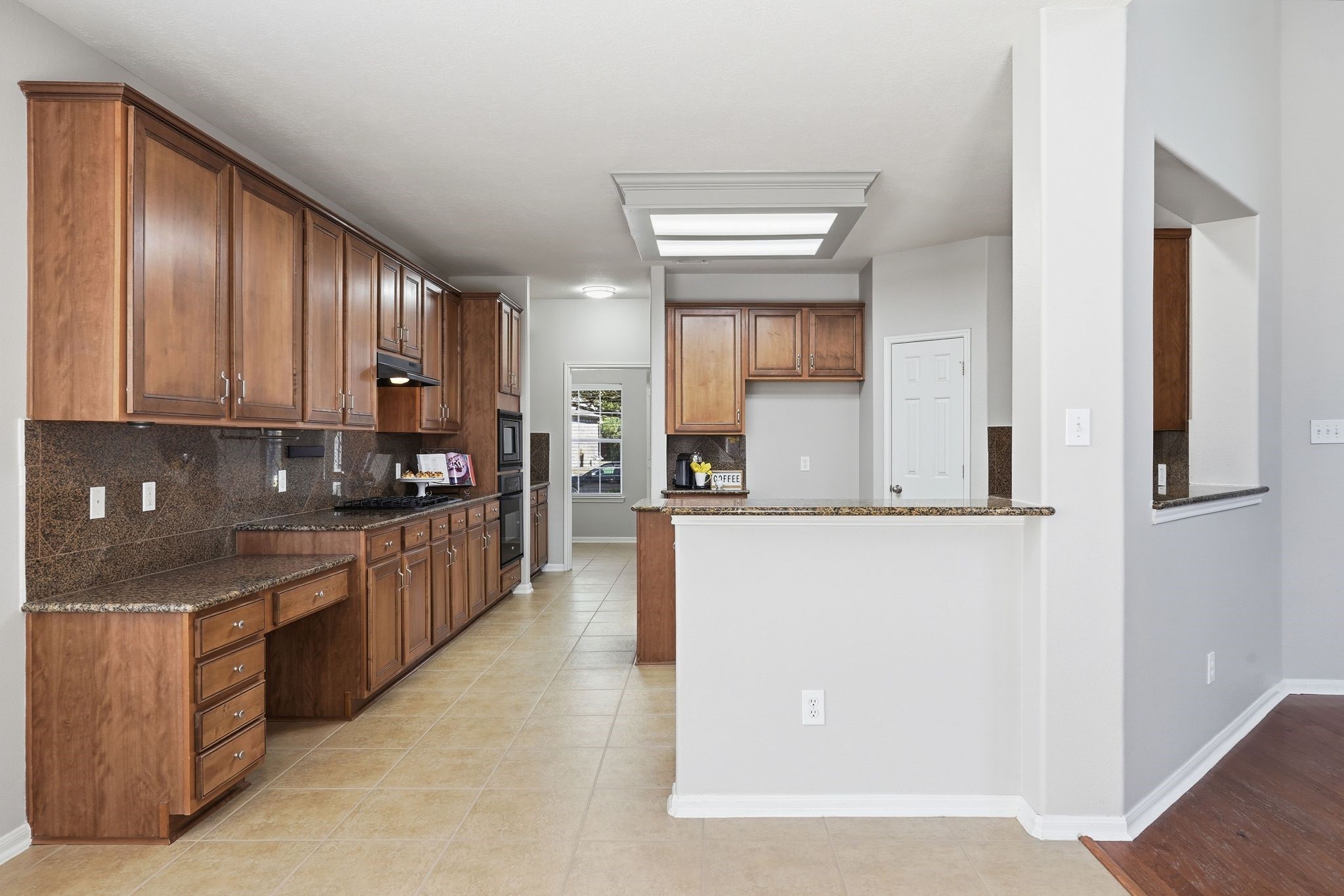 24931 Corbin Gate Drive Spring, TX 77389 - Photo 18 of 50 Spacious kitchen featuring ample wooden cabinetry, granite countertops, and a tile floor. Includes built-in appliances and a cozy breakfast bar.