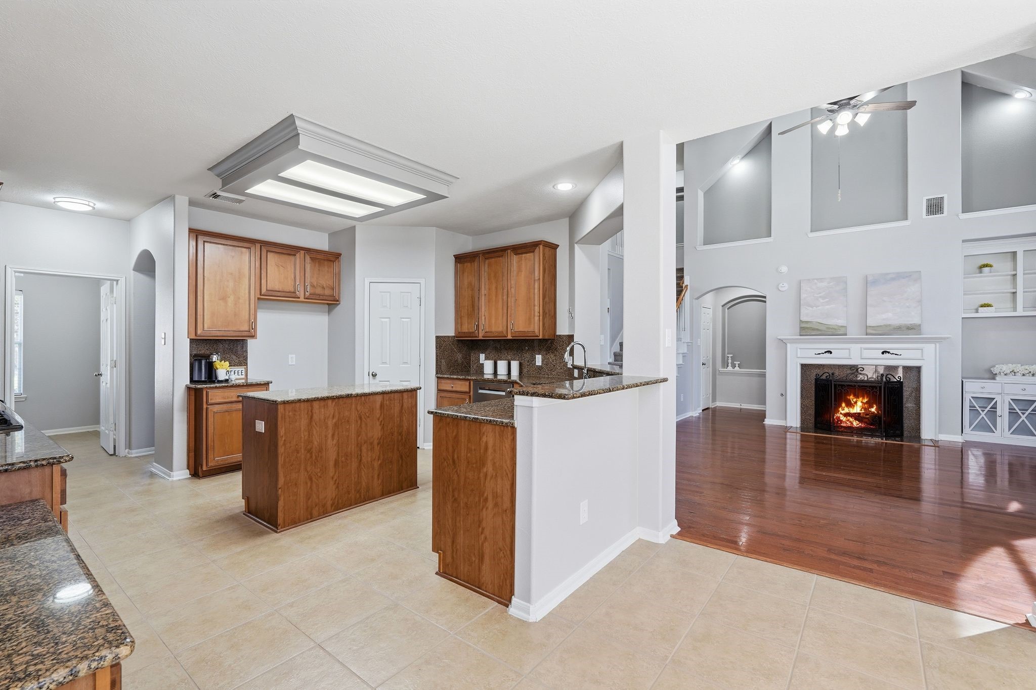 24931 Corbin Gate Drive Spring, TX 77389 - Photo 20 of 50 This inviting home features an open-concept layout with a spacious kitchen boasting granite countertops and wood cabinetry. The living area includes a cozy fireplace, high ceilings, and ample natural light, creating a warm, welcoming atmosphere.