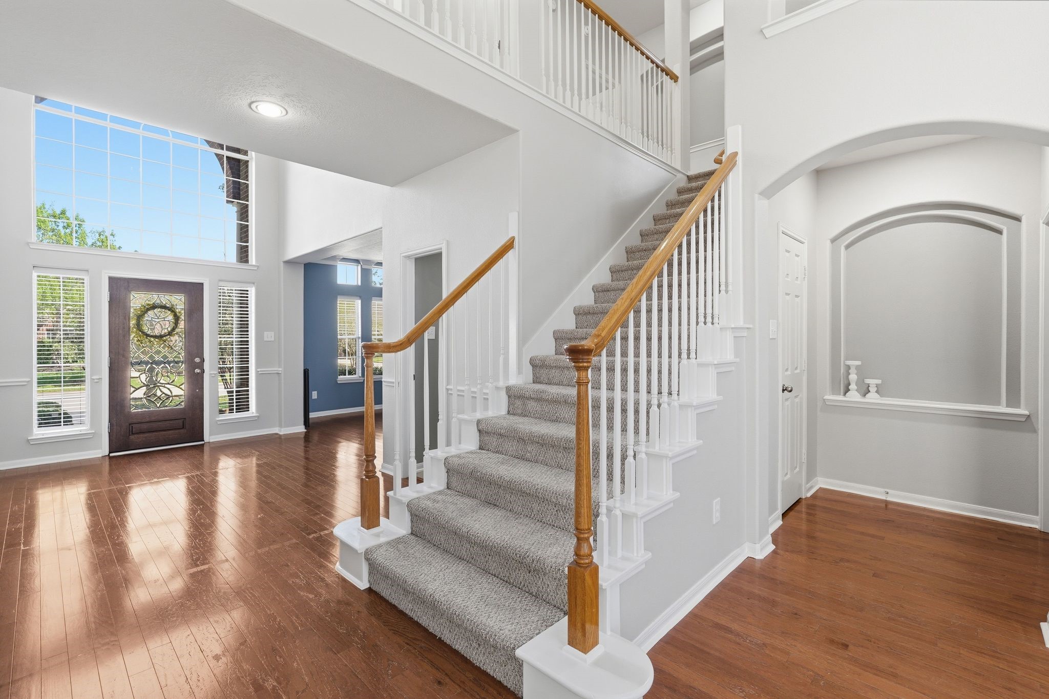 24931 Corbin Gate Drive Spring, TX 77389 - Photo 23 of 50 This inviting entryway features a bright, open space with high ceilings and a staircase with wooden handrails. The large windows and elegant front door allow natural light to fill the area, highlighting the hardwood floors.