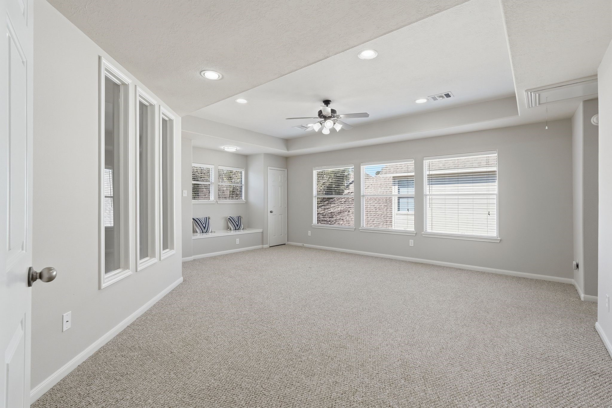 24931 Corbin Gate Drive Spring, TX 77389 - Photo 27 of 50 This spacious game room room features neutral carpeting, recessed lighting, and a ceiling fan. Large windows offer ample natural light, and a cozy nook with built-in seating adds charm. Ideal for a bright and inviting living space.