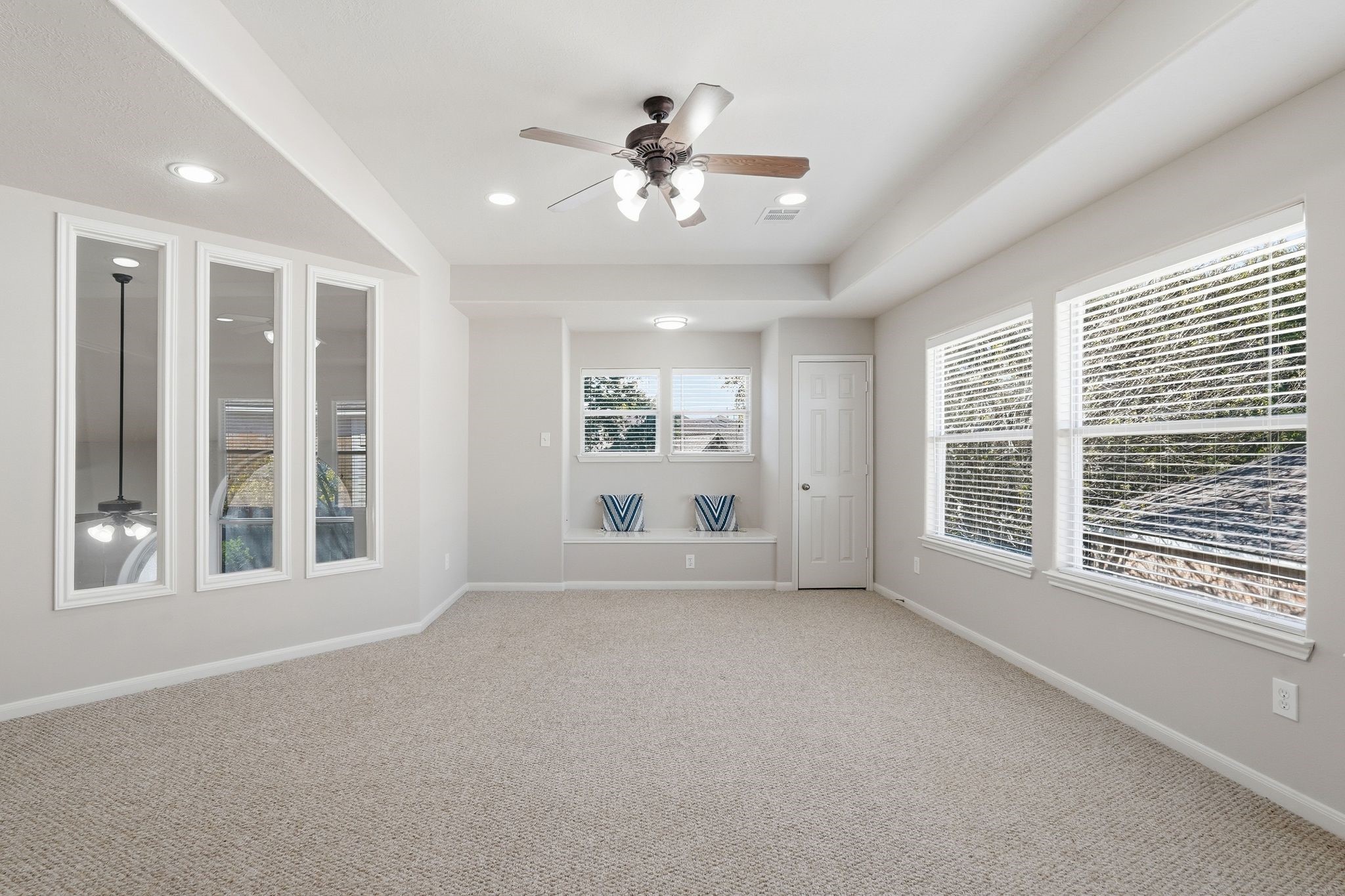 24931 Corbin Gate Drive Spring, TX 77389 - Photo 28 of 50 This spacious room features neutral carpeting, large windows with abundant natural light, a ceiling fan, and a built-in bench. The room is well-lit with recessed lighting, and there's a door leading to additional space.