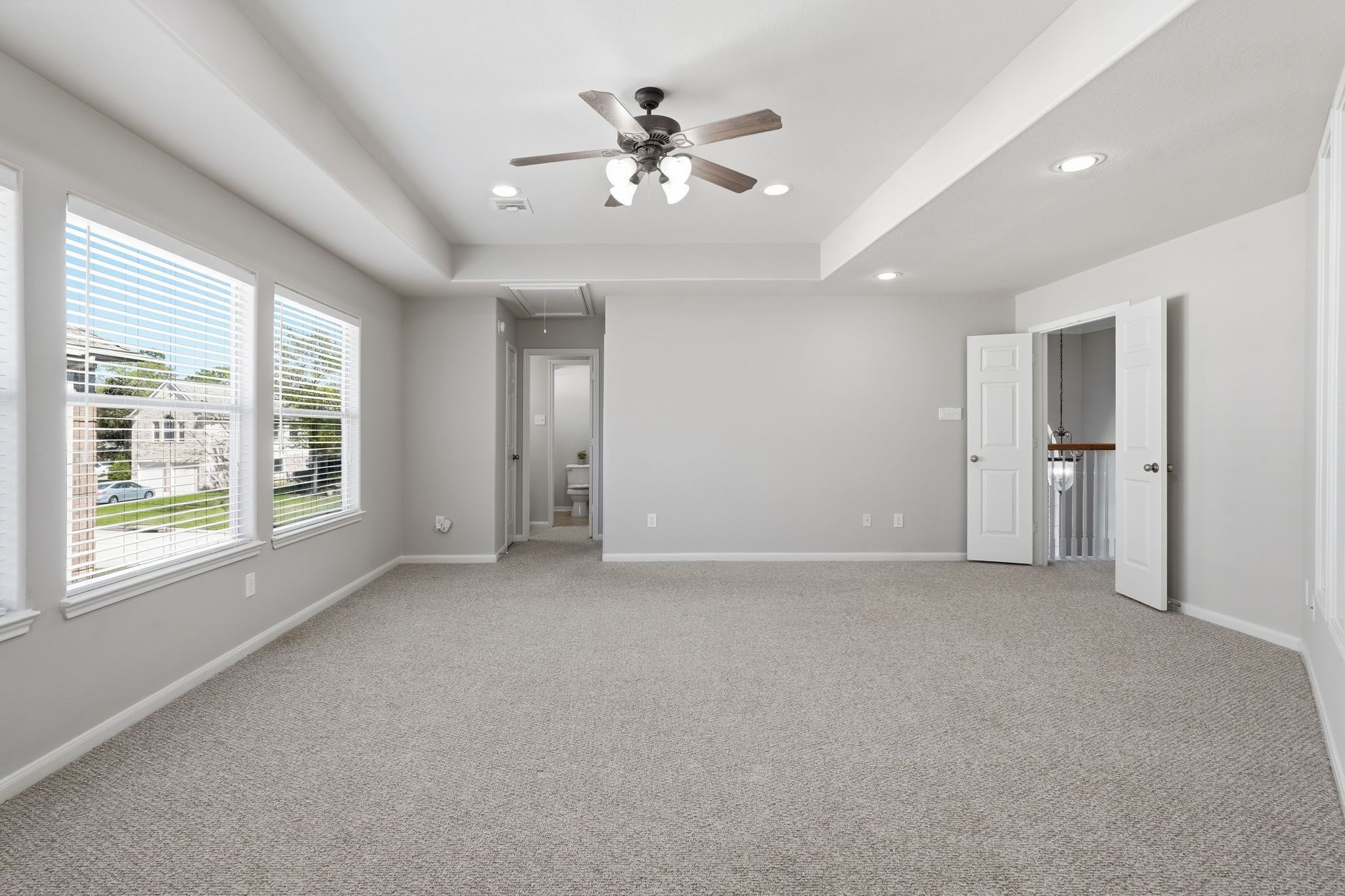 24931 Corbin Gate Drive Spring, TX 77389 - Photo 29 of 50 Spacious, carpeted game room with neutral tones, featuring large windows for natural light, a ceiling fan, and an adjacent bedroom and bathroom.