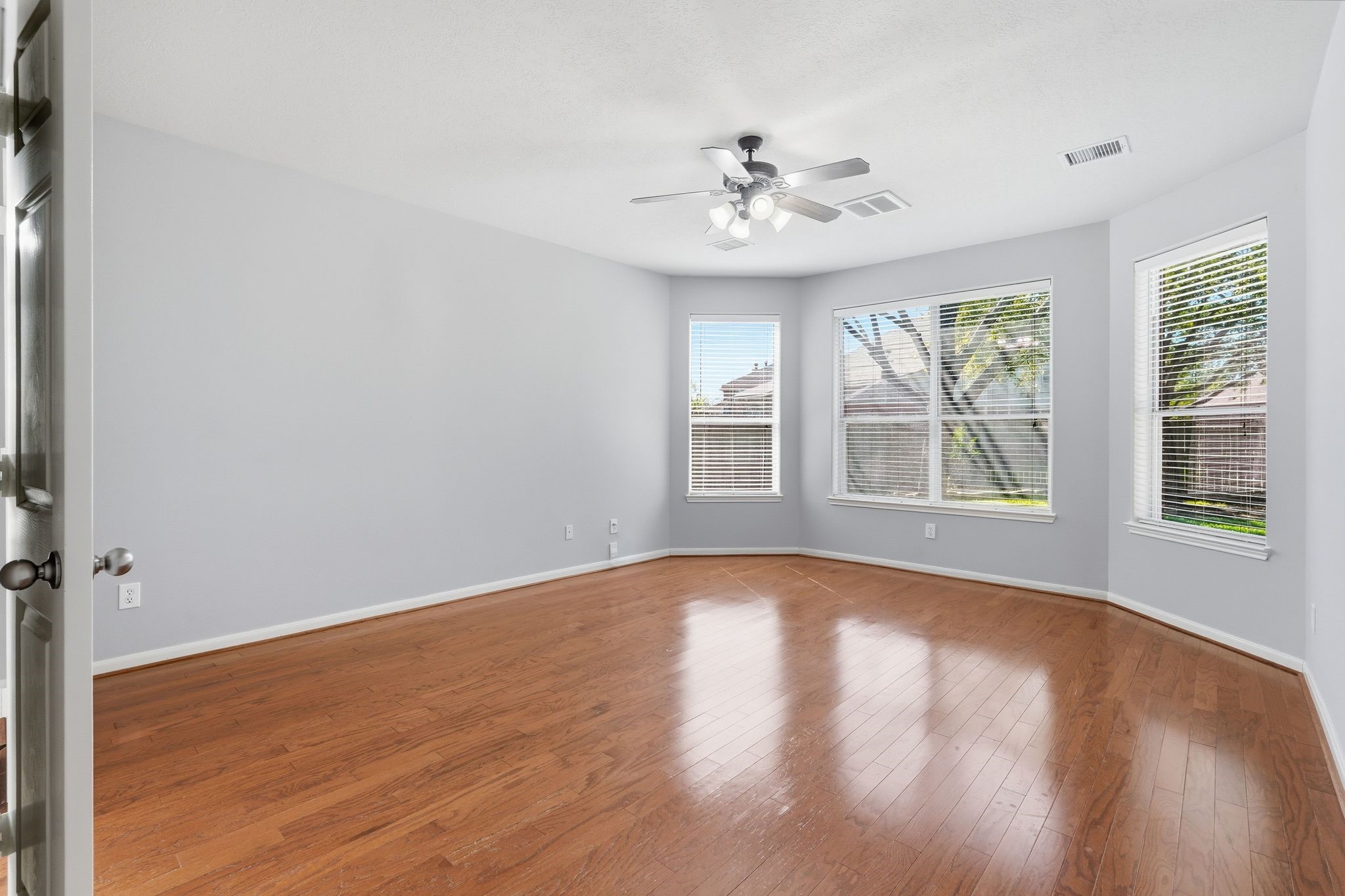 24931 Corbin Gate Drive Spring, TX 77389 - Photo 31 of 50 The spacious primary bedroom features hardwood floors, large windows, a sitting area, ceiling fan, and offers plenty of natural light.